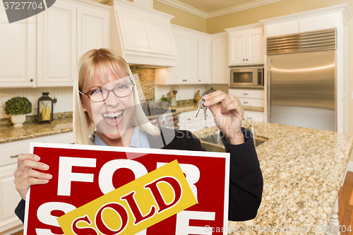 Image of Young Woman Holding Sold Sign and Keys Inside New Kitchen