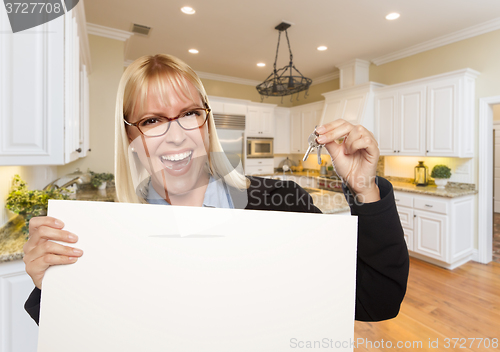 Image of Young Woman Holding Blank Sign and Keys Inside Kitchen