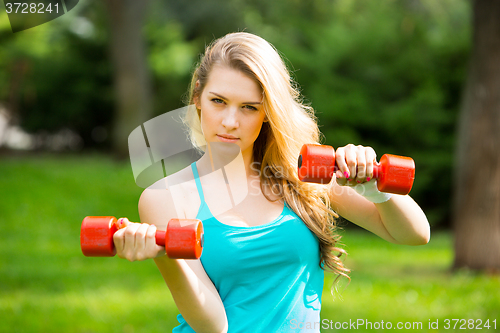 Image of Sports girl exercise with  dumbbells in the park