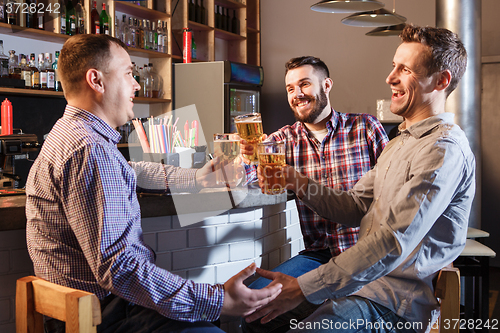 Image of Happy friends drinking beer at counter in pub