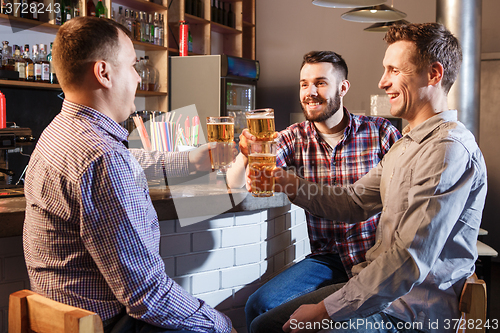 Image of Happy friends drinking beer at counter in pub