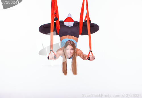 Image of Young woman doing anti-gravity aerial yoga in hammock