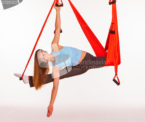Image of Young woman doing anti-gravity aerial yoga in hammock