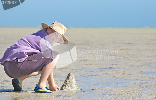 Image of teenager making sandcastles on the beach