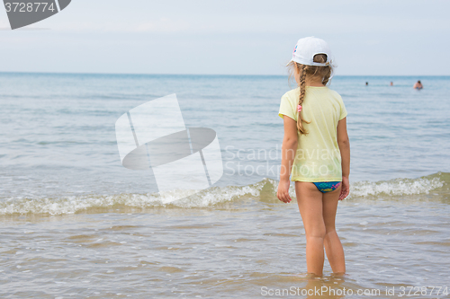 Image of A girl stands on the shore and looks into the distance to the sea