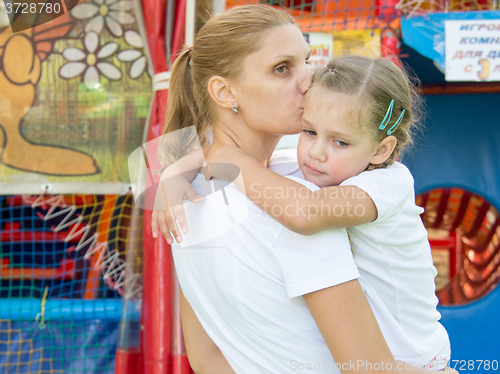 Image of Young mother hugs and kisses tired three-year daughter had a soft gaming room