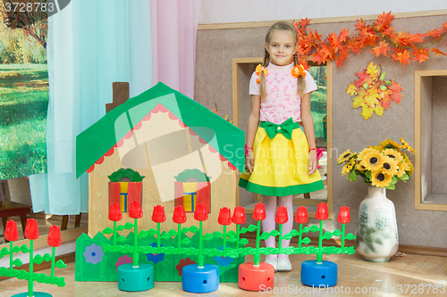 Image of  A girl stands at the scenery house on matinee in kindergarten