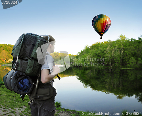 Image of Backpacking hiker encounters a hot air balloon floating above a 