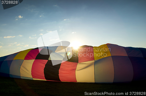 Image of Sun peaking over the inflating envelope of a hot air balloon