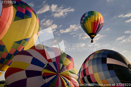 Image of Hot air balloon floating over other inflating balloons