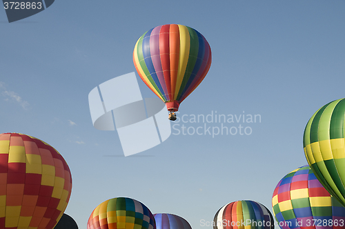 Image of Single hot-air balloon floating above a balloon festival