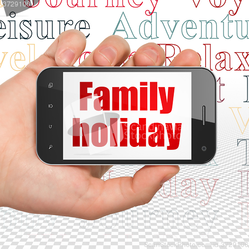 Image of Travel concept: Hand Holding Smartphone with Family Holiday on display