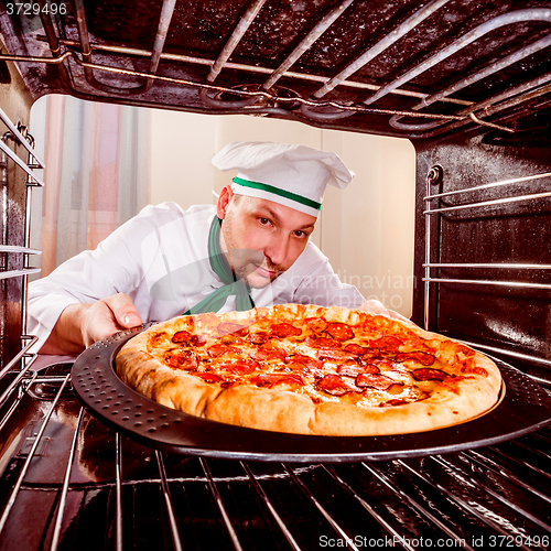 Image of Chef cooking pizza in the oven.