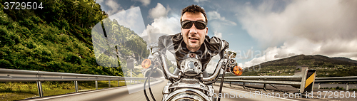 Image of Funny Biker in sunglasses and leather jacket racing on mountain 