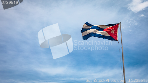 Image of Cuban flag flying in the wind on a backdrop of blue sky.