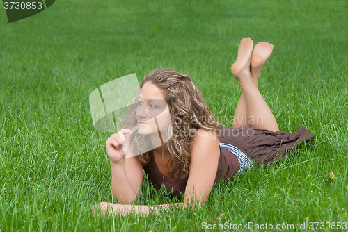 Image of Attractive girl relaxes on grass