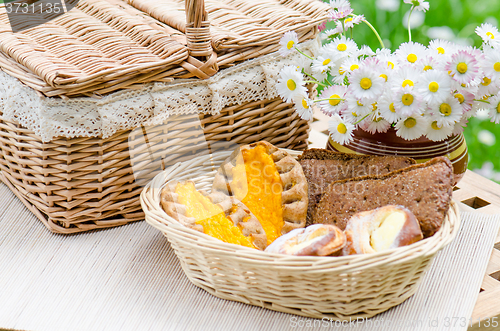 Image of Buns in a wicker basket and a bouquet of flowers