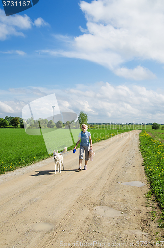 Image of Woman with a dog goes on a country road  