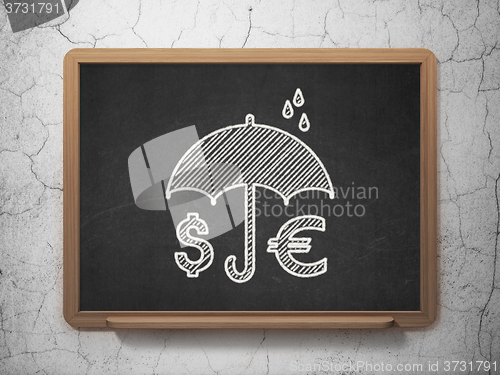 Image of Protection concept: Money And Umbrella on chalkboard background