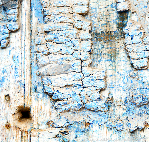 Image of metal nail dirty stripped paint in the brown wood door and rusty