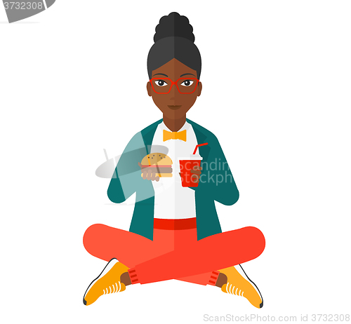 Image of Woman eating hamburger. 