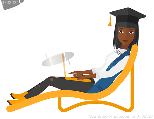 Image of Graduate lying in chaise lounge with laptop.