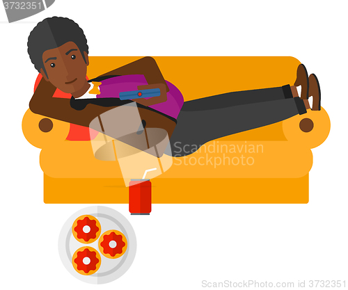 Image of Man lying on sofa with junk food.