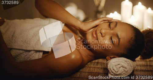 Image of Woman Lying On Massage Table And Touching Her Face