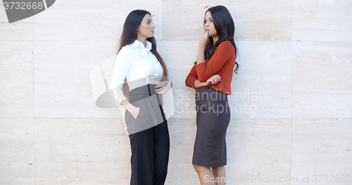 Image of Two businesswomen standing chatting outdoors