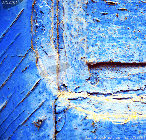 Image of dirty stripped paint in the blue wood door and rusty nail