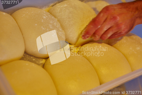 Image of Small balls of fresh homemade pizza dough on floured wooden board 