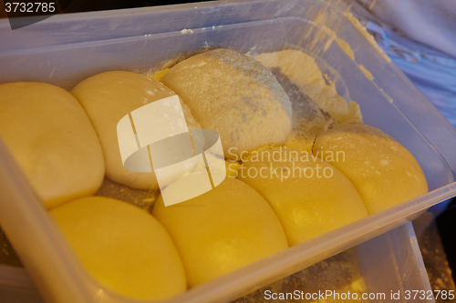 Image of Small balls of fresh homemade pizza dough on floured wooden board 