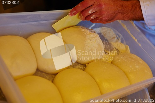 Image of Small balls of fresh homemade pizza dough on floured wooden board 