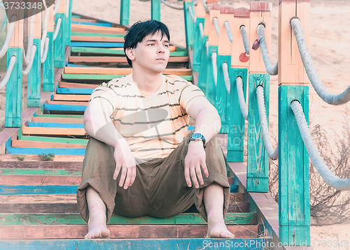 Image of A young man sitting on the steps