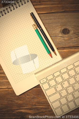 Image of notebook on a spring, vintage pencil, pen and computer keyboard