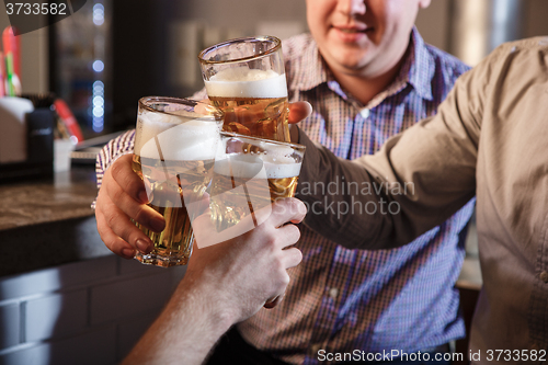 Image of Happy friends drinking beer at counter in pub