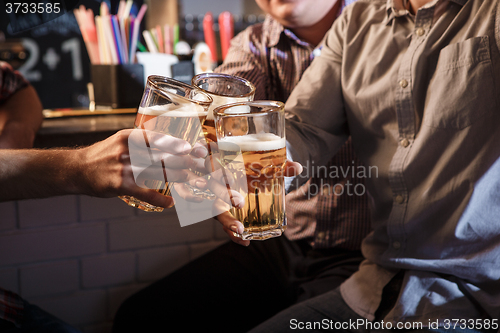 Image of Happy friends drinking beer at counter in pub