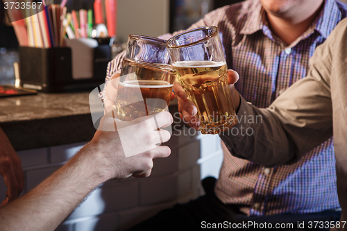 Image of Happy friends drinking beer at counter in pub