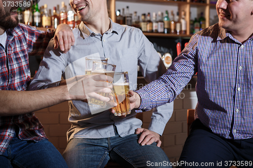 Image of Happy friends drinking beer at counter in pub