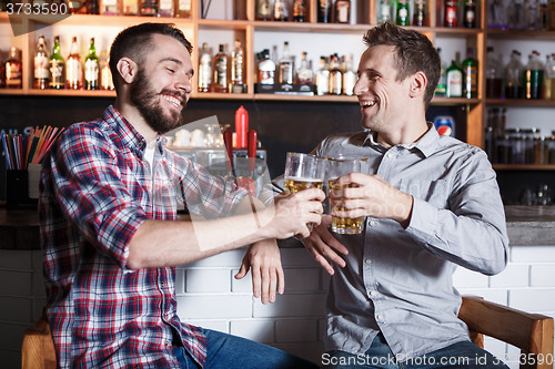 Image of Happy friends drinking beer at counter in pub