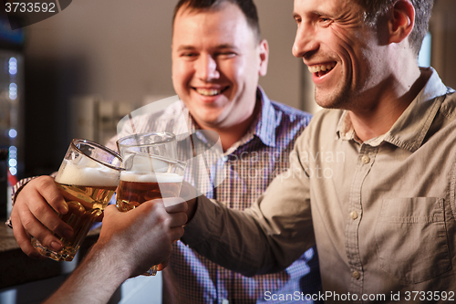 Image of Happy friends drinking beer at counter in pub