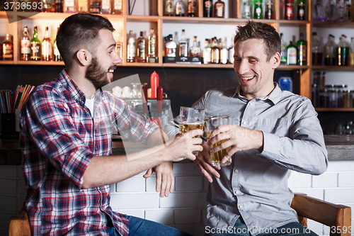 Image of Happy friends drinking beer at counter in pub