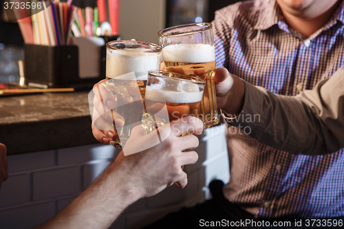Image of Happy friends drinking beer at counter in pub