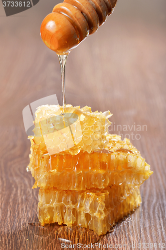 Image of Honey dripping on honeycombs on wooden background