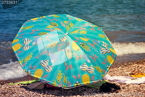 Image of Sunshades and clothes on a sea beach  