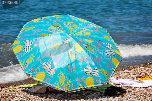 Image of Sunshades and clothes on a sea beach  