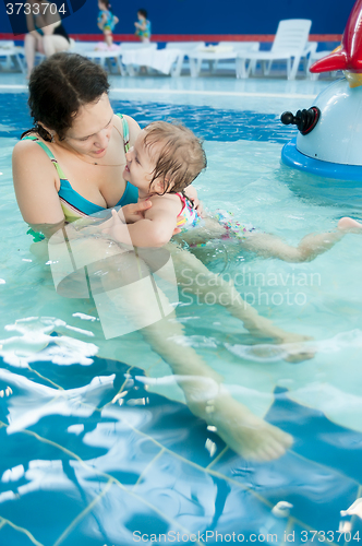 Image of Mother talks little daughter something in water