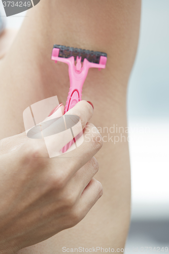 Image of Woman shaving armpit