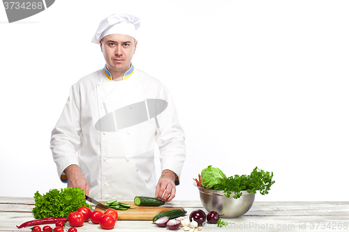 Image of Chef cutting a green cucumber in his kitchen