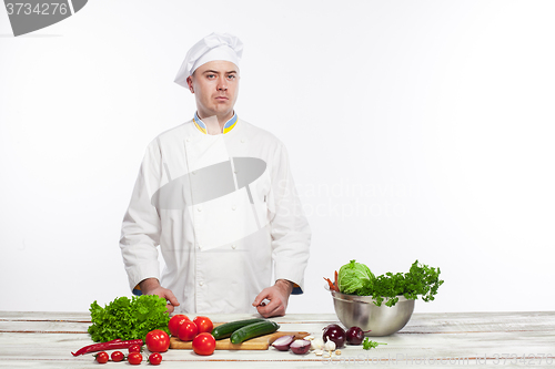 Image of Chef cutting a green cucumber in his kitchen